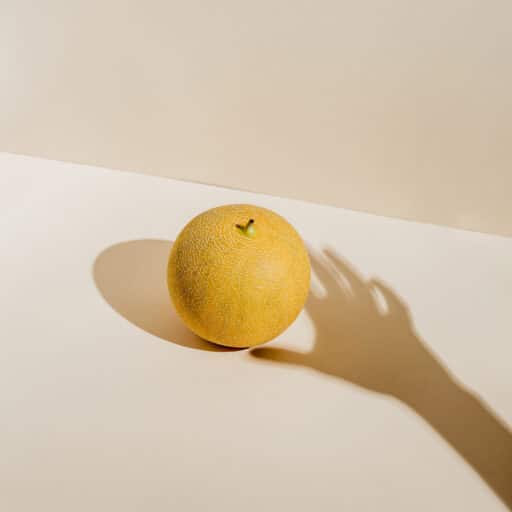 Shadow of a hand reaching towards lemon