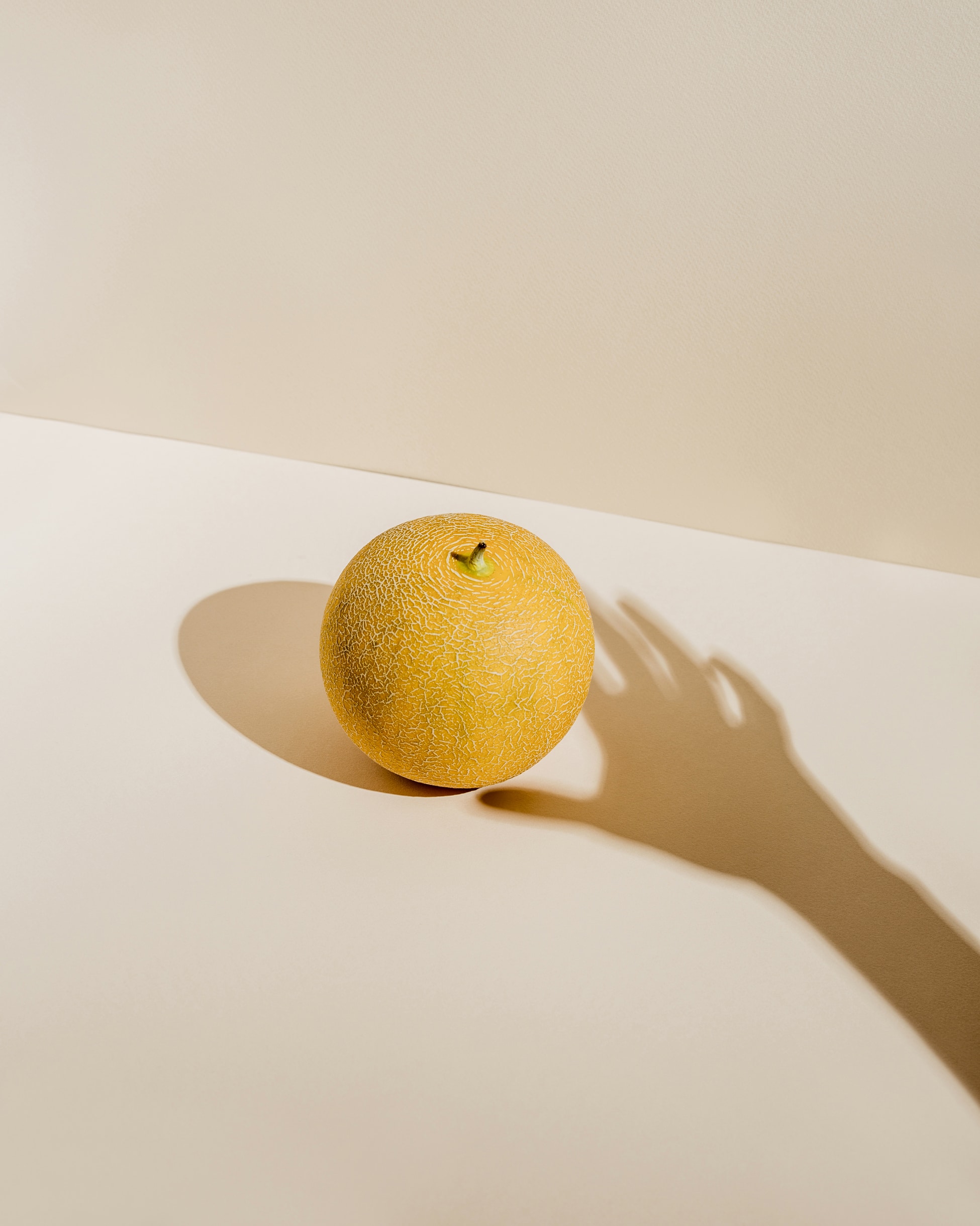 Shadow of a hand reaching towards lemon